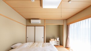 Un dormitorio con cama, armario, mesita de noche y ventana con cortinas.
