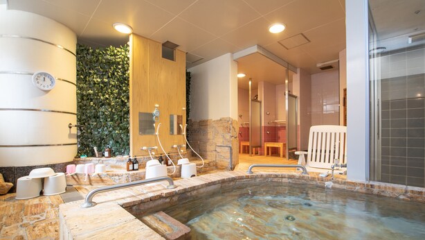 Zona de spa con hidromasaje, armarios de madera y una pared con follaje verde.