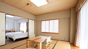 Una habitación japonesa tradicional con suelo de tatami, una mesa baja, una cama y una puerta corredera.
