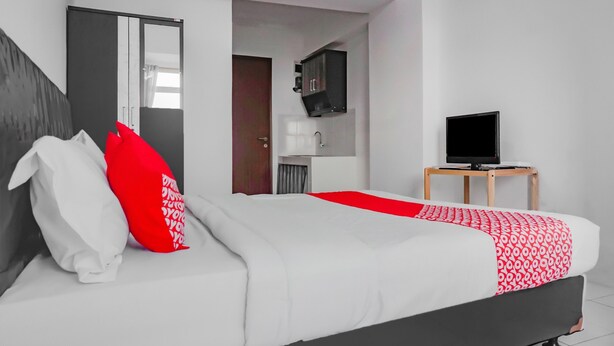 Ein modernes Hotelzimmer mit einem großen Bett, einem Fernseher und einem kleinen Schreibtisch.