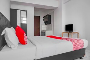 A modern hotel room with a large bed, a television, and a small desk. - OYO 90241 SIROOMS Apartmen Gunung Putri (Gunung Putri)