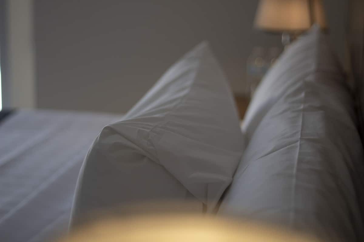 Primer plano de una cama con ropa de cama y almohadas blancas.