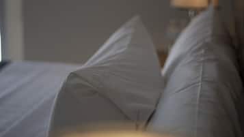 Primer plano de una cama con ropa de cama y almohadas blancas.