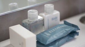 Uma bancada de banheiro com um dosador de sabonete branco, um sabonete azul e uma garrafa de shampoo azul.