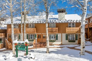 A traditional wooden building with balconies, a snow-covered roof, and a sign indicating a parking area.