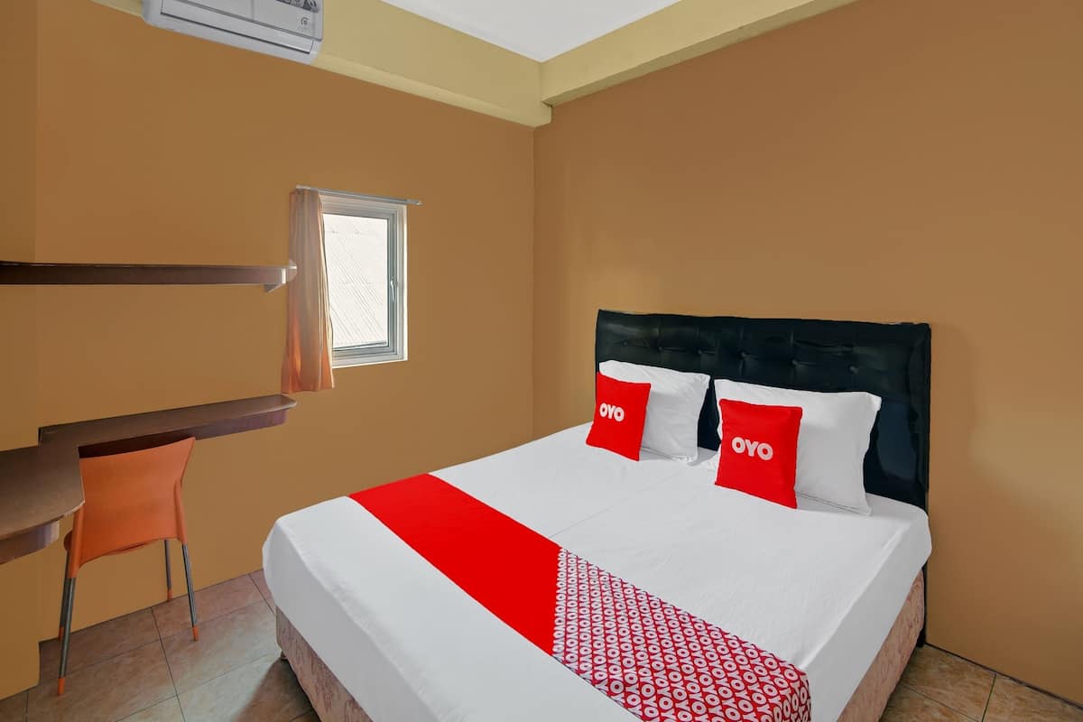A hotel room with a bed, a desk, and a chair.