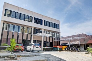 A modern building with a two-story structure, large windows, and a covered parking area. - OYO 90499 Hotel Fortune (Manado)