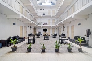 A spacious atrium with a high ceiling, multiple seating areas, and potted plants. - OYO 90499 Hotel Fortune (Manado)