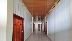 A long, narrow hallway with wooden doors on one side and white paneling on the other. - OYO Life 92291 Hotel Cahaya Syariah (Tungkal Ilir)
