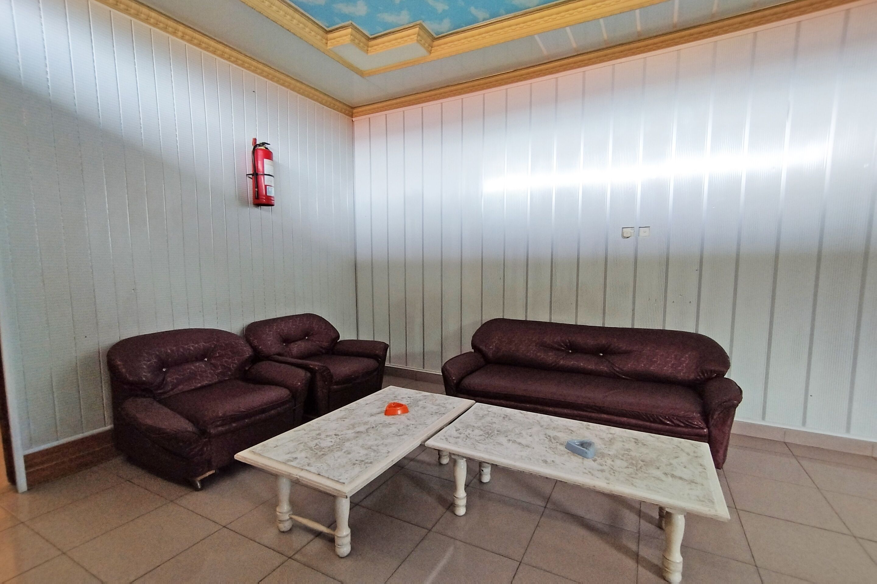 Ein Zimmer mit zwei dunkelbraunen Sofas, einem weißen Marmor-Couchtisch und einer Decke mit Holzvertäfelung und einem blauen Anstrich.