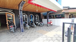 A hotel entrance with a tiled floor, a wooden ceiling, and several motorcycles parked outside. - OYO Life 92291 Hotel Cahaya Syariah (Tungkal Ilir)
