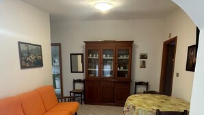 A living room with a sofa, a dining table with chairs, a cabinet, and a ceiling light.
