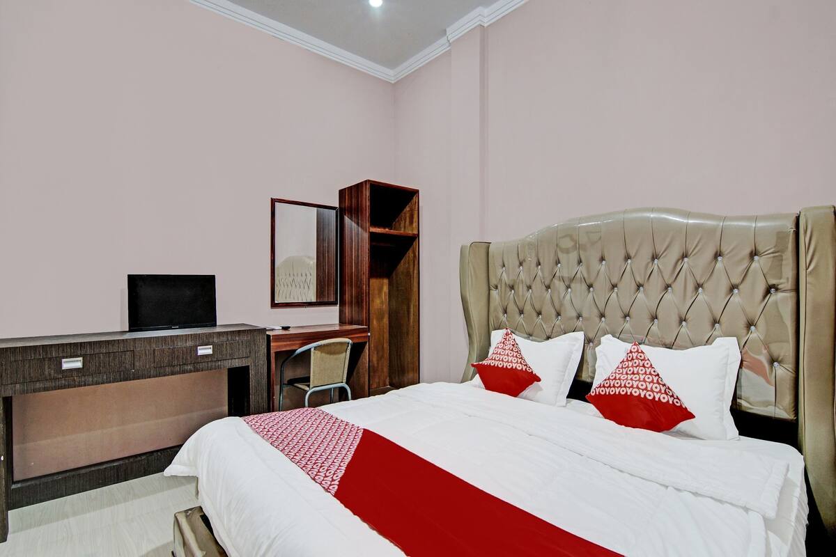 A hotel room with a bed, a desk, a chair, and a television.