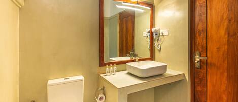 A bathroom with a toilet, sink, mirror, and wooden door.