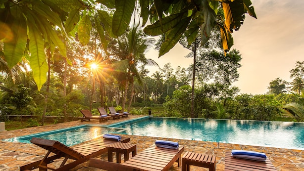 Un espace aménagé au bord de la piscine, avec des chaises longues en bois et une terrasse dallée de pierres.