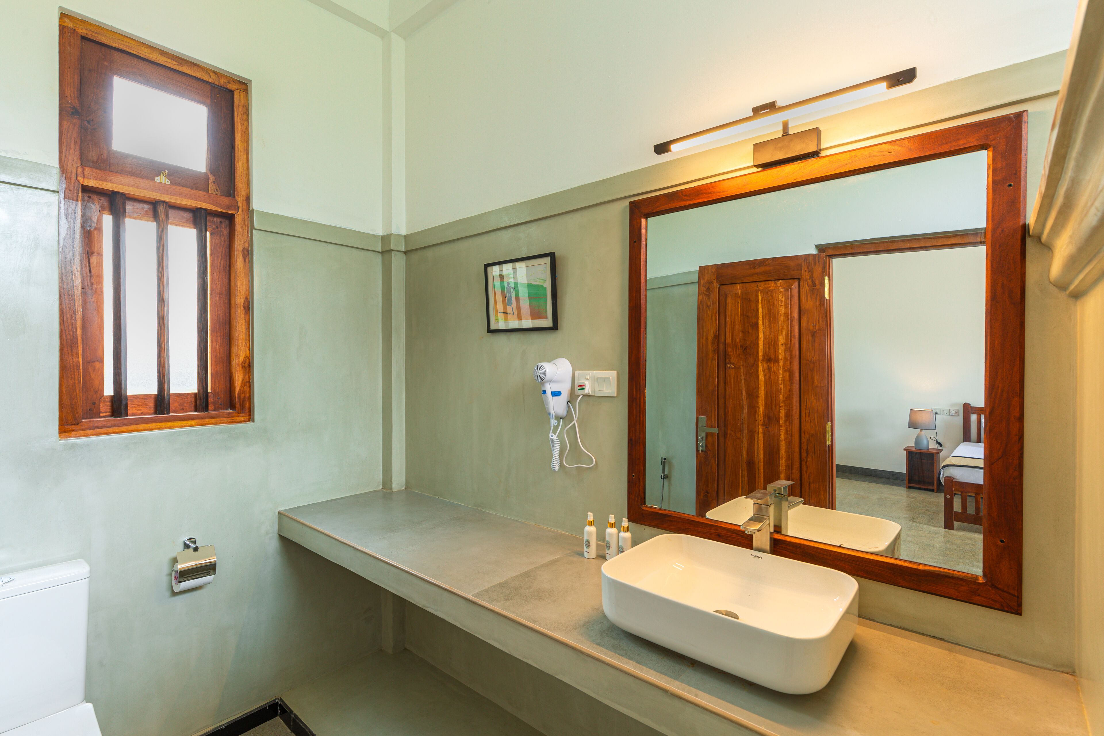 A bathroom with a large mirror, a sink, and a window.