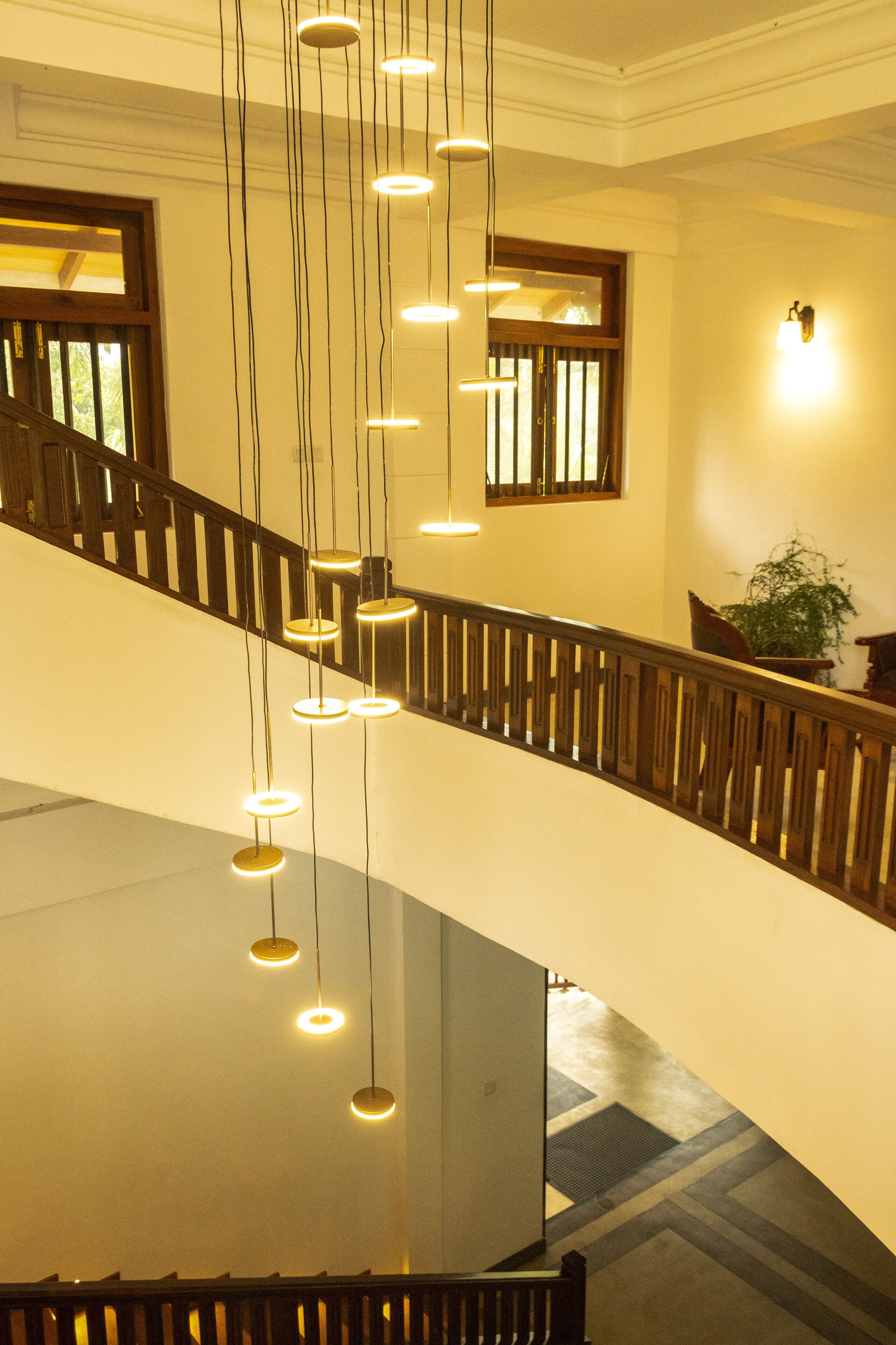 Un intérieur à plusieurs niveaux, doté d’un escalier, de rampes en bois et de luminaires suspendus.