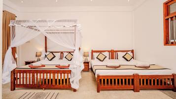 A hotel room with two wooden beds, each with a canopy, white linens, and decorative pillows.