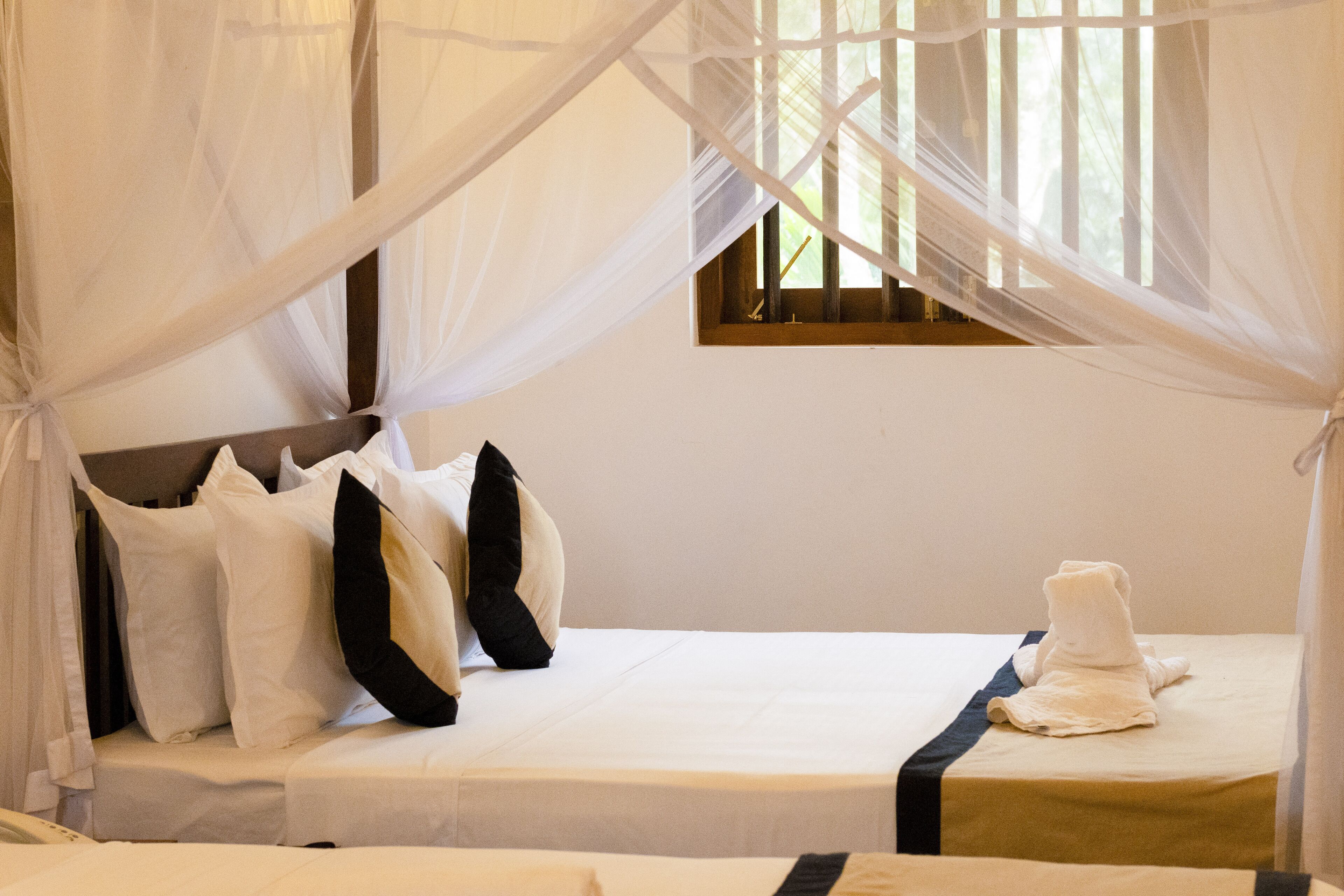Una cama con ropa de cama blanca, almohadas negras y blancas, y una toalla blanca.