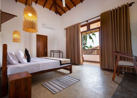 Un dormitorio con cama, muebles de madera, una mesita pequeña, una silla, una lámpara colgante y vistas al exterior.