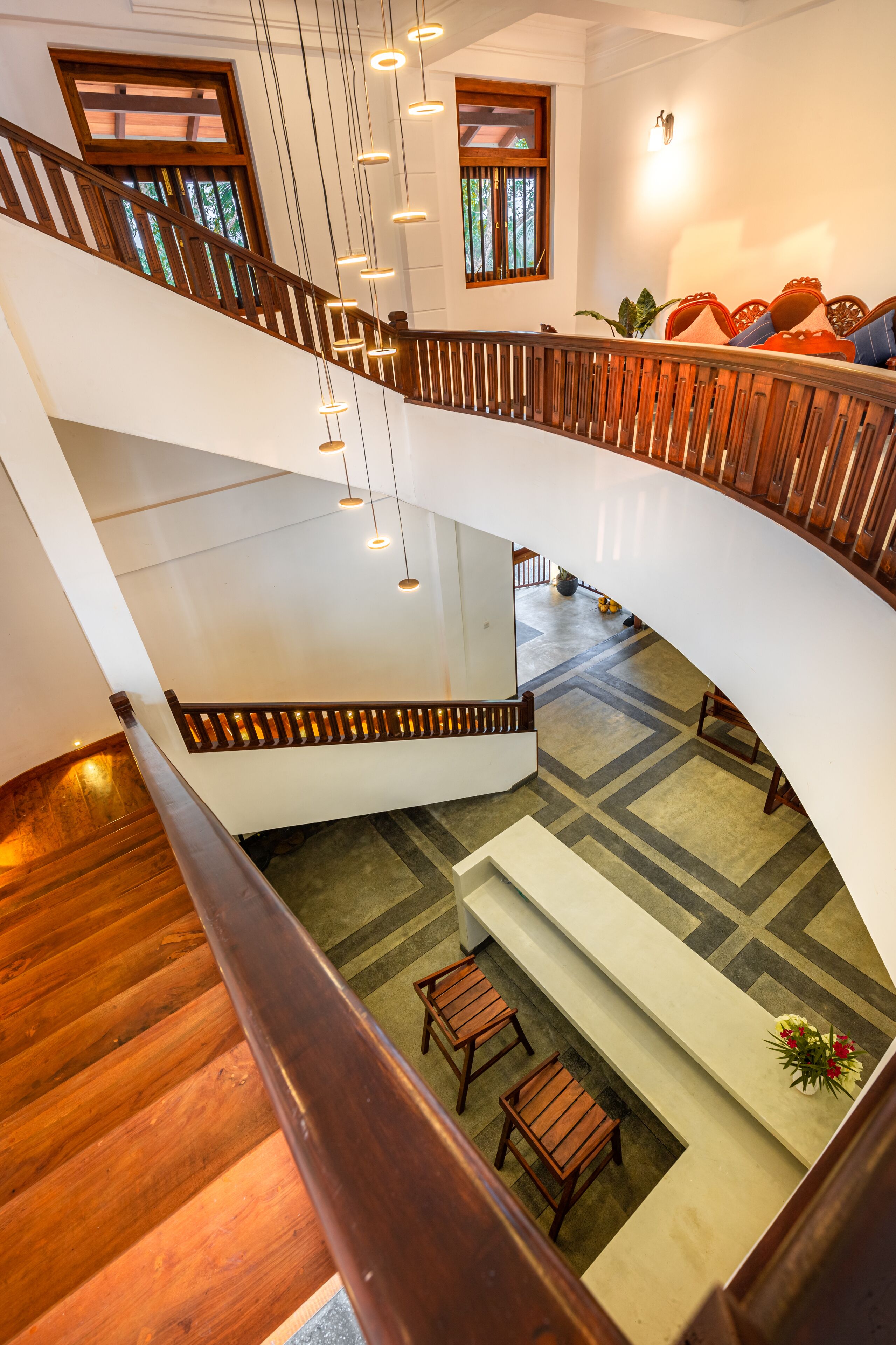 A multi-level interior with wooden flooring, a central staircase, and a seating area with a bench and chairs.