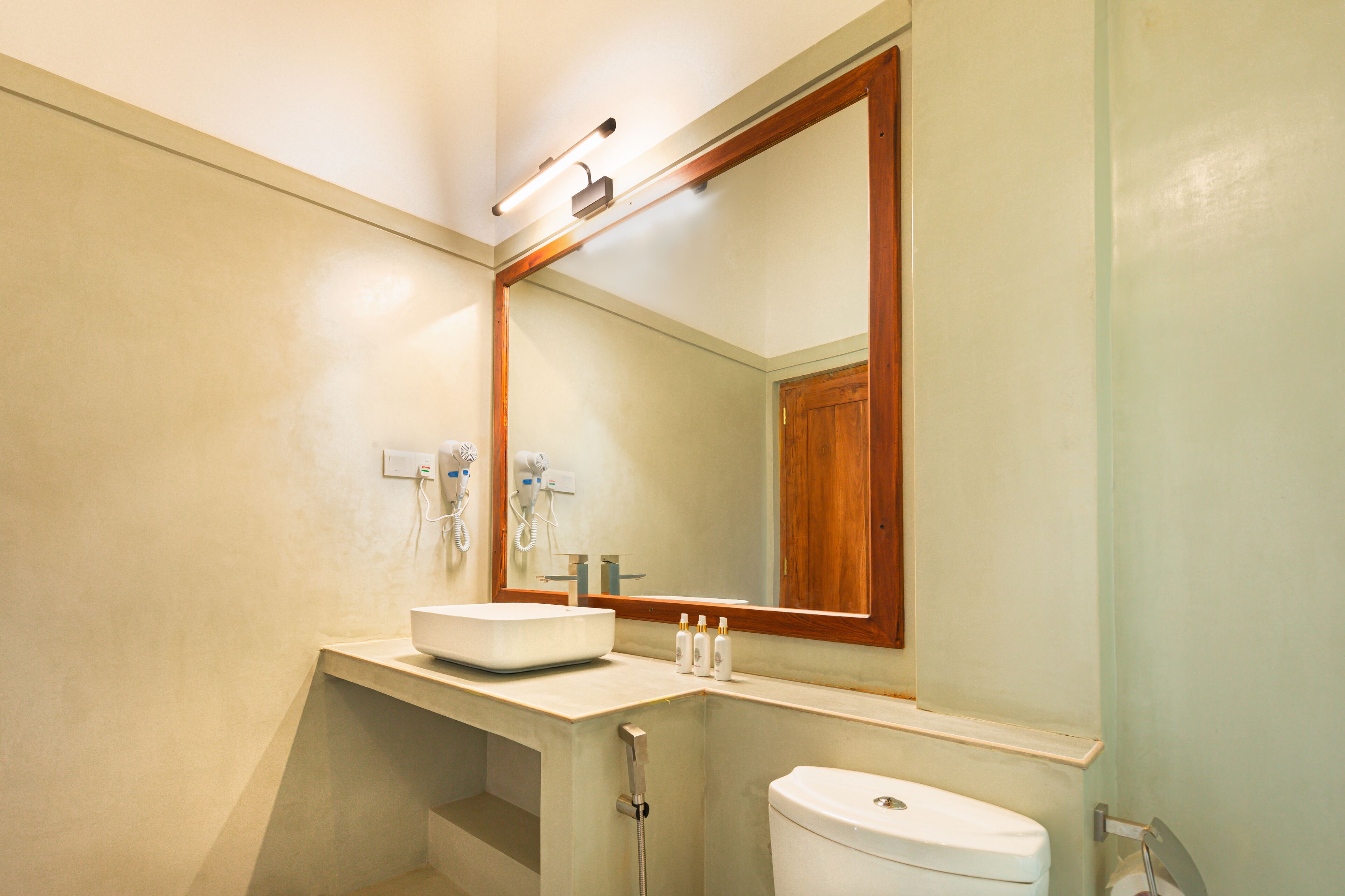 A bathroom with a white sink, a mirror, and a toilet.