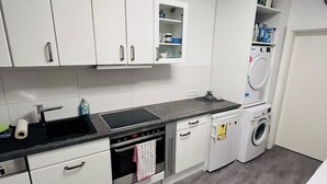 Cocina moderna con armarios blancos, horno empotrado, lavabo y lavadora.