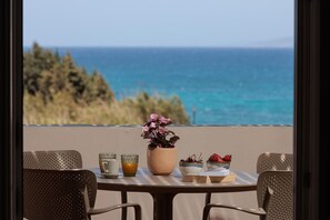 A table with a view of the ocean, a potted plant, and a bowl of strawberries. - 9 Muses Naxos beach hotel (Naxos)