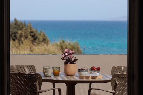 A table with a view of the ocean, a potted plant, and a bowl of strawberries. - 9 Muses Naxos beach hotel (Naxos)