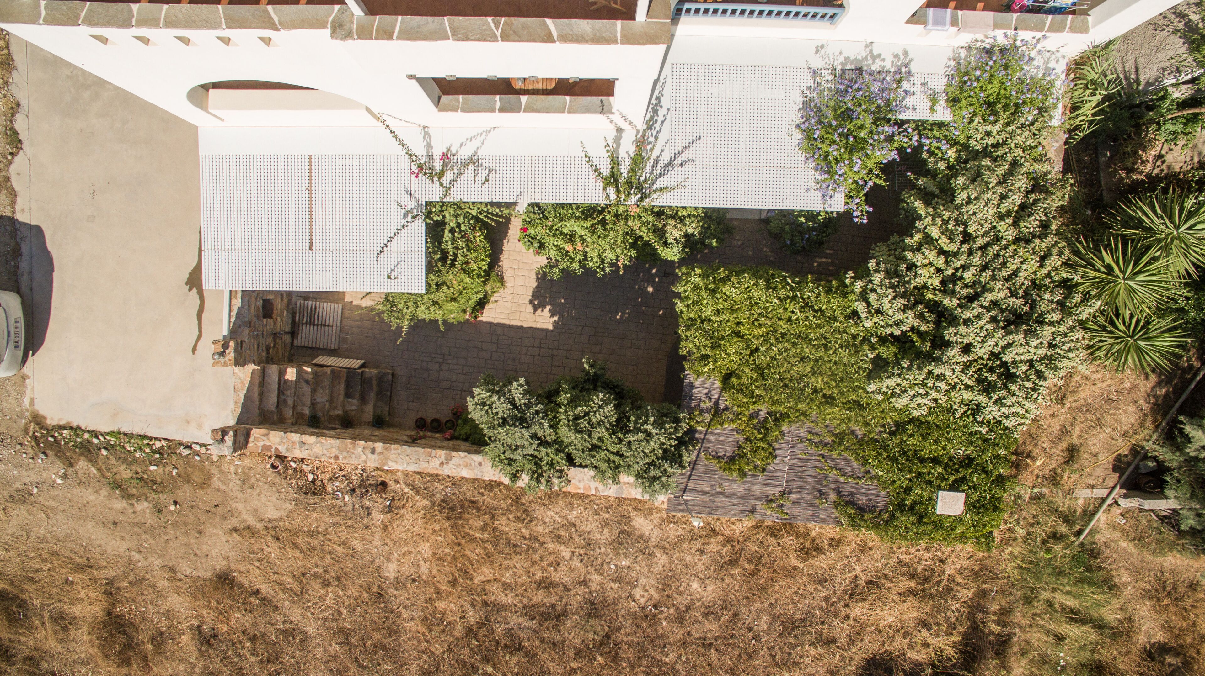 An aerial view of a building with a courtyard, stone walls, and various plants.
