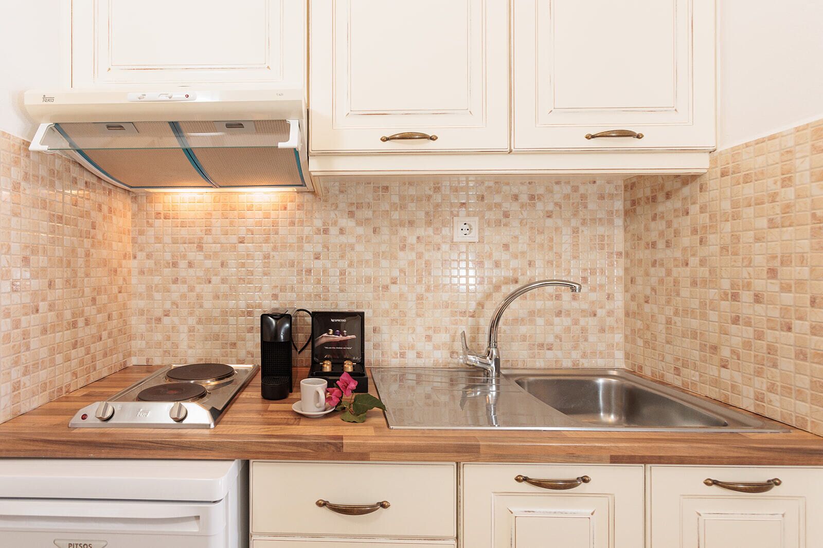 A kitchen with white cabinets, a stainless steel sink, a coffee maker, and a toaster.