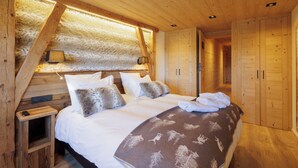 A wooden bedroom with a bed, pillows, a blanket, and a nightstand. - Le Refuge Cal Chalon ***** chalet in the heart of the village - its breathtaking view (Les Angles)