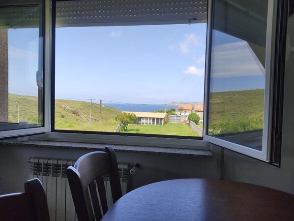A room with a large window overlooking a grassy landscape and a body of water.