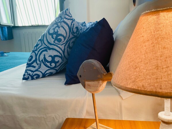 A bed with patterned pillows, a lamp, and a wooden nightstand.