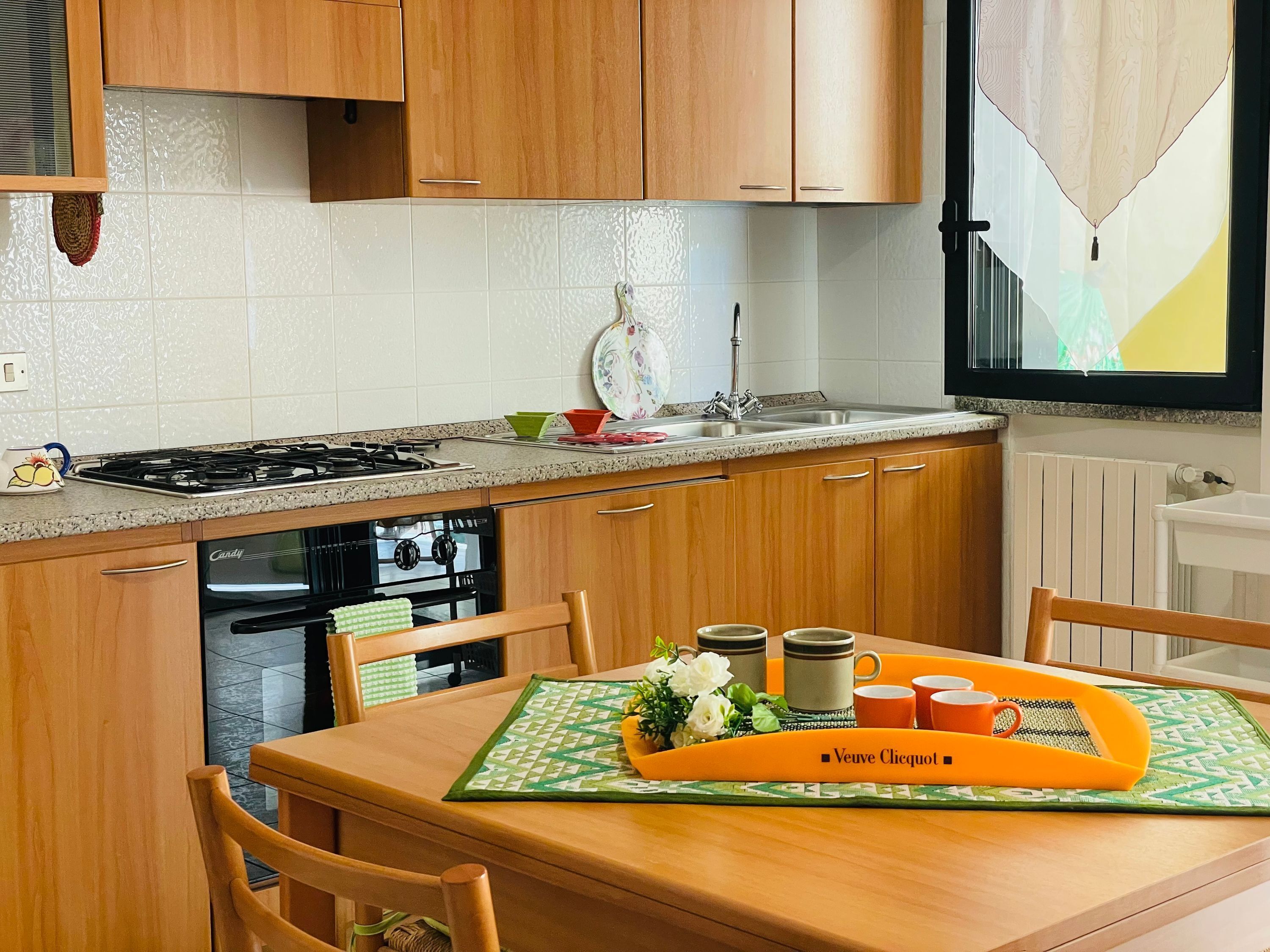 A kitchen with wooden cabinets, a stove, and a dining table set with a placemat and cups.