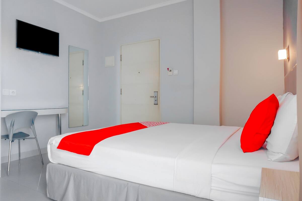 Quarto de hotel moderno com uma cama, uma mesa e uma cadeira.