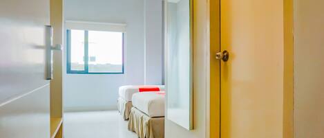 A hotel room with a large window, a bed, a bedside table, and a wardrobe.