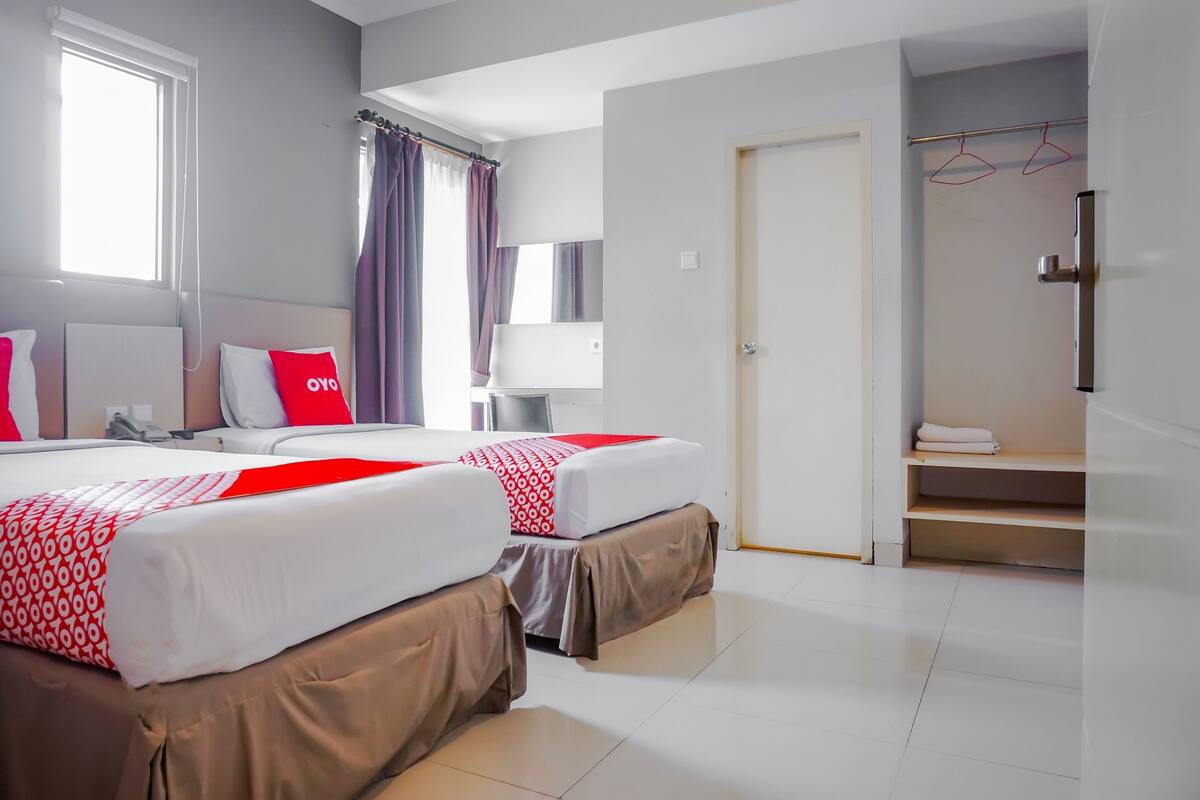 Quarto de hotel com duas camas, banheiro e porta que dá para um corredor.