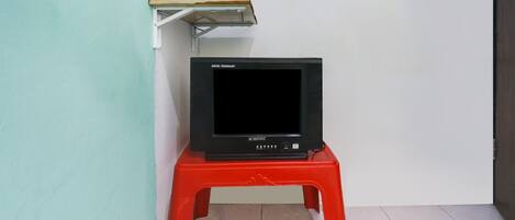 A black television on a red stool against a teal wall.