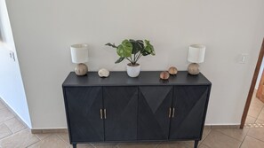 A black console table with two wall-mounted lamps, a potted plant, and decorative items.
