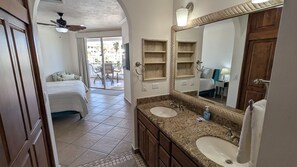 A hotel bathroom with two sinks, a large mirror, and a ceiling fan.