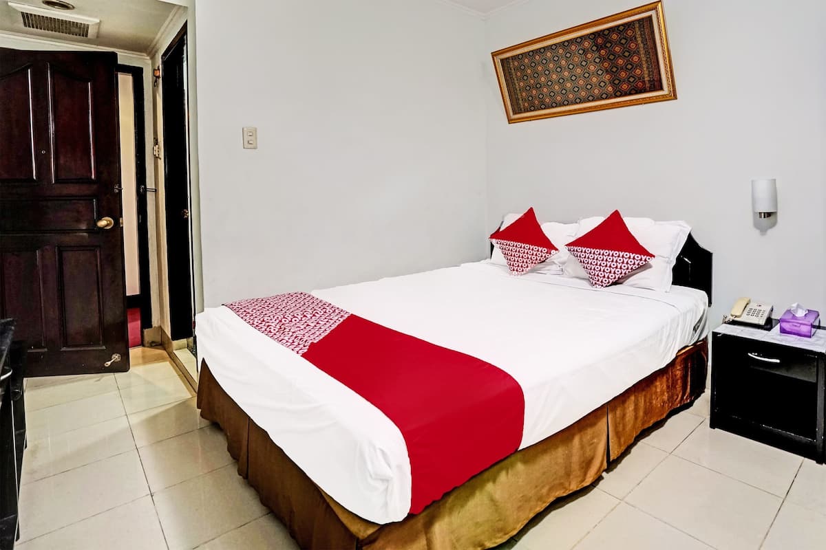 Une chambre d’hôtel comprenant un lit, une table de chevet, un téléphone et un luminaire fixé au mur.