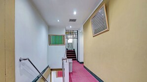 Un pasillo con alfombra roja, una escalera con barandilla de metal y un diseño decorativo en la pared.