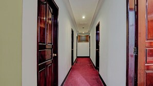 Un pasillo con puertas de madera, alfombra roja y un cuadro enmarcado en la pared.