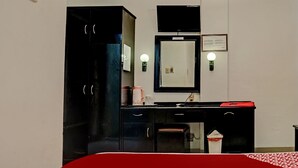 Habitación de hotel con cama, escritorio con espejo, armario negro y televisor instalado en la pared.