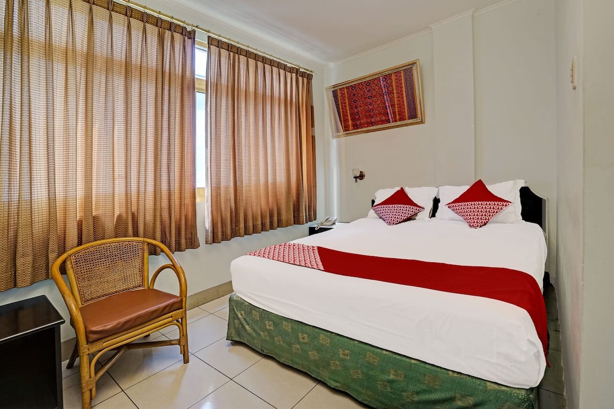 Une chambre d’hôtel avec un lit, une chaise, un bureau et des rideaux.