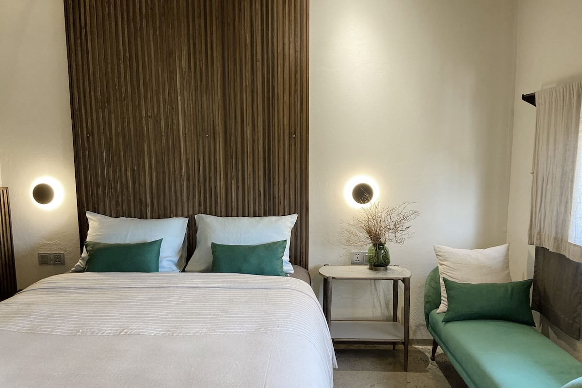 A bedroom with a bed, bedside tables, and a sofa.