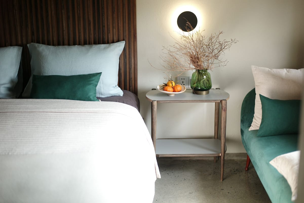 A hotel room with a bed, bedside table, and a green sofa.