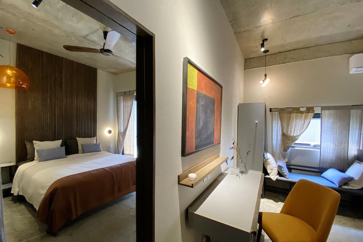 A hotel room with a bed, desk, chair, and a large mirror.