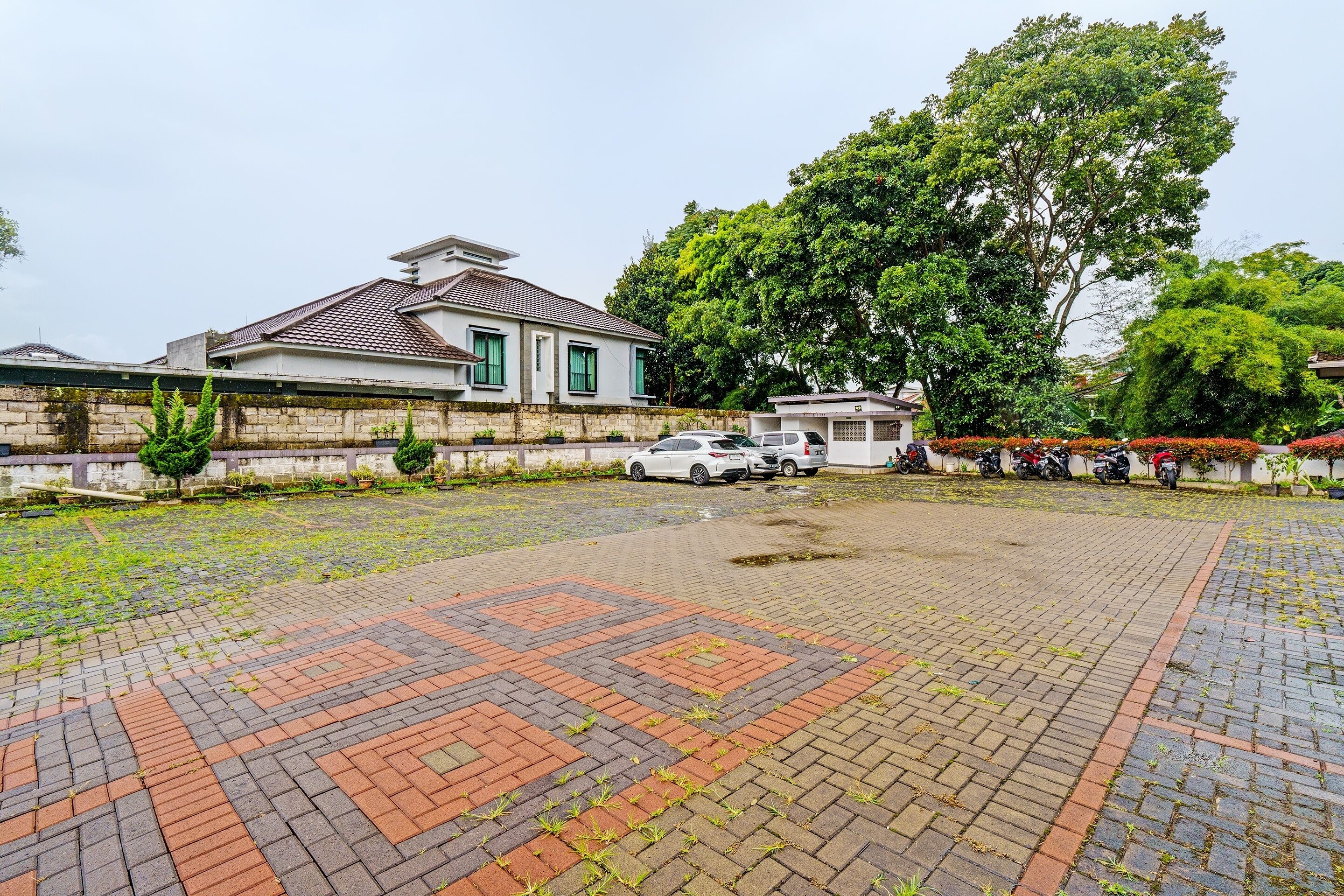 A paved courtyard with a patterned design, surrounded by buildings and parked cars.